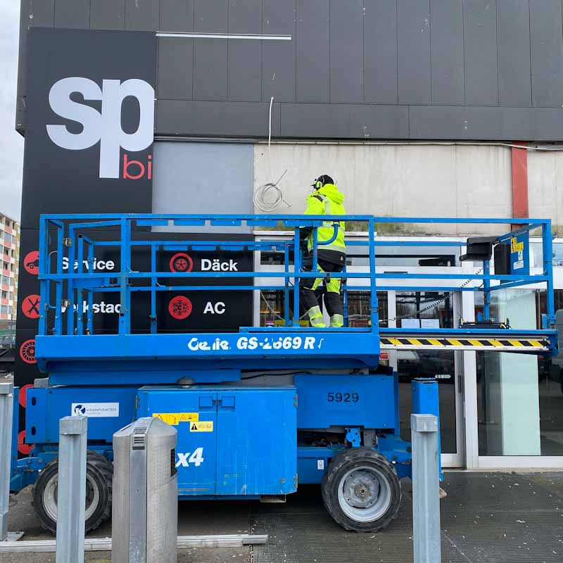 Facade sign installation using a scissor lift